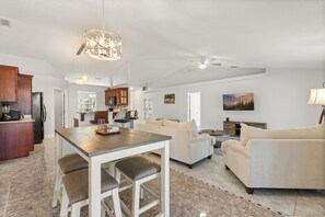 A spacious living area with a dining table, sofas, and a kitchen in the background. - Charming Kissimmee Retreat Near Orlando (Kissimmee)