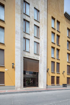 Un bâtiment doté de nombreuses fenêtres, d’une entrée au niveau du sol et d’une enseigne indiquant l’adresse, bien visible.