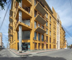Ein mehrstöckiges gelbes Gebäude mit Balkonen, einem sichtbaren Schaufenster und einem Verbotsschild für Parkplätze.