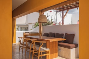 A dining area with a wooden table and chairs, a woven light fixture, and a cushioned bench. - Upscale penthouse apartment - Soul of the City. (Santa Marta)