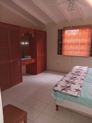 A bedroom with a bed, a wardrobe, and a window with blinds. - Budget bungalow across the road from the calm west coast sandy beach (Paynes Bay Beach)