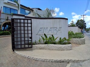 A sign for AMARA RESTAURANT with a metal gate and plants around it. - Budget bungalow across the road from the calm west coast sandy beach (Paynes Bay Beach)