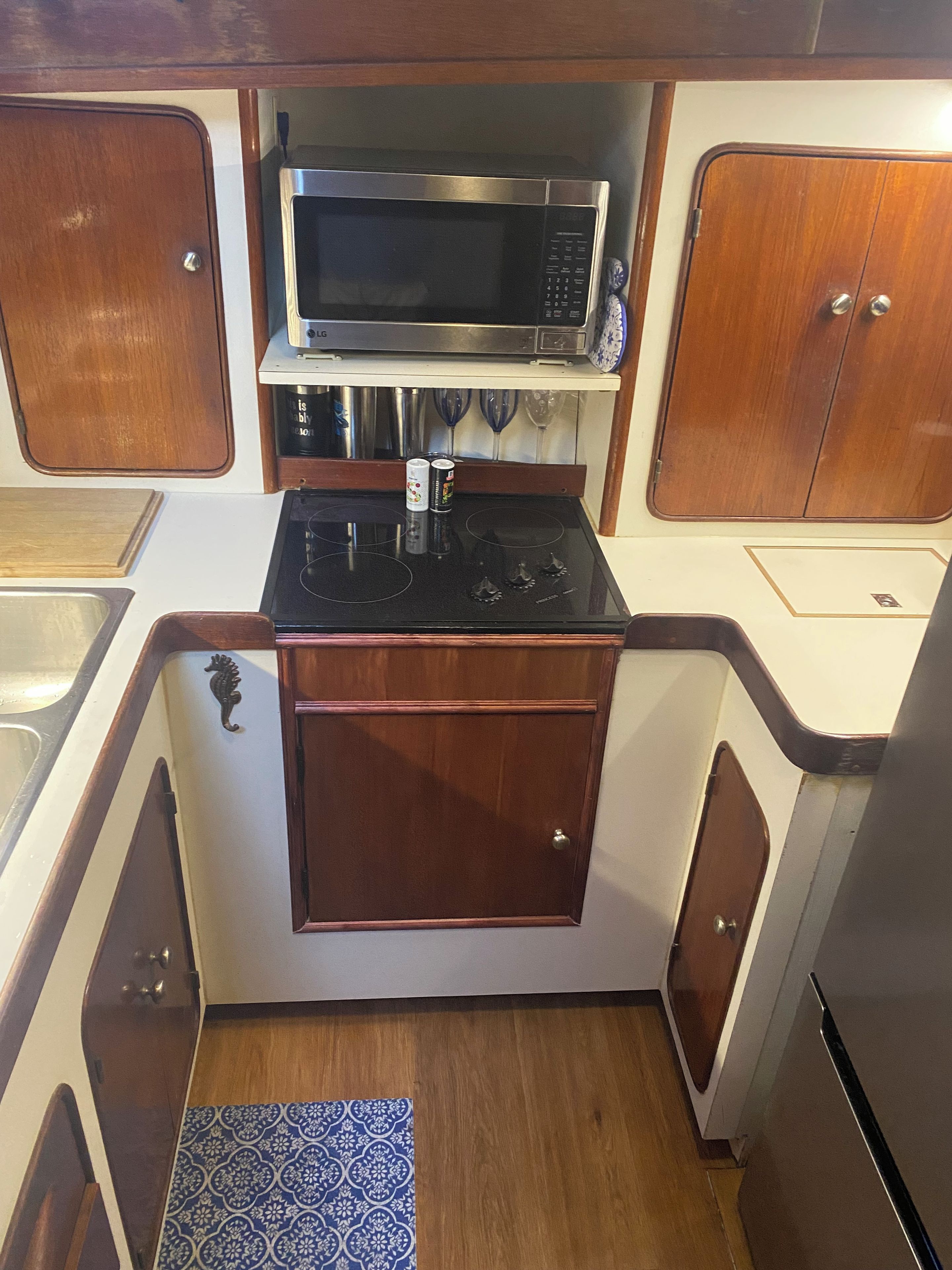 Una cocina compacta con microondas, estufa y armarios de madera.