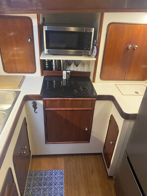 Una cocina compacta con microondas, estufa y armarios de madera.