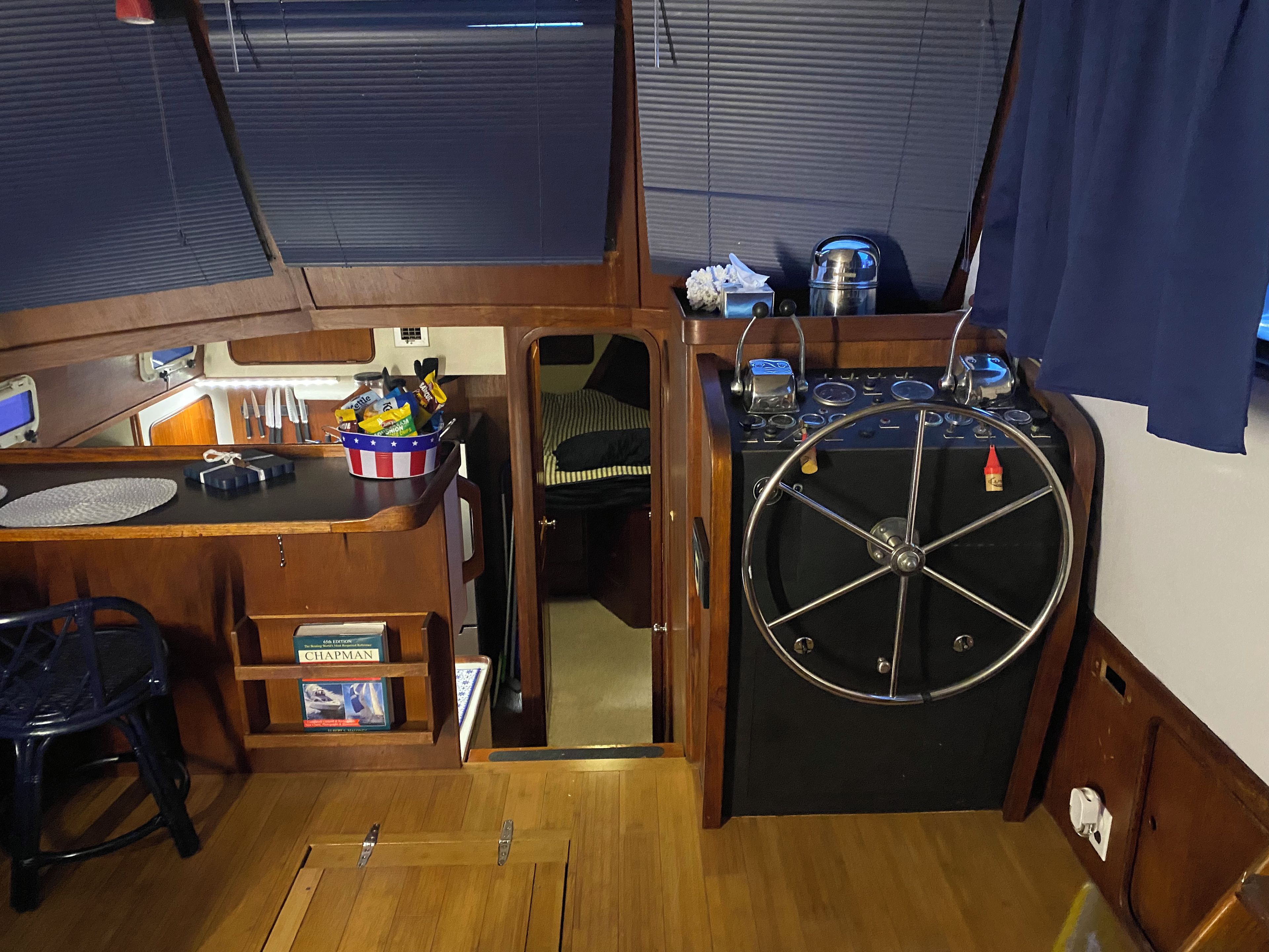 Une petite cabine équipée d’un volant, d’un petit évier et d’une étagère contenant des livres et des collations.