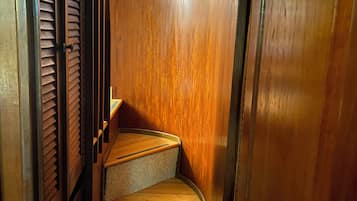 Una stretta scala in legno con un pianerottolo rivestito di moquette, che conduce a un livello superiore.