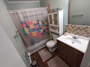 Un baño con inodoro, lavabo y cortina de ducha con un mapa de los Estados Unidos.