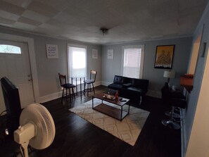 Ein Wohnzimmer mit einer Couch, zwei Sesseln, einem Couchtisch und einem Ventilator.
