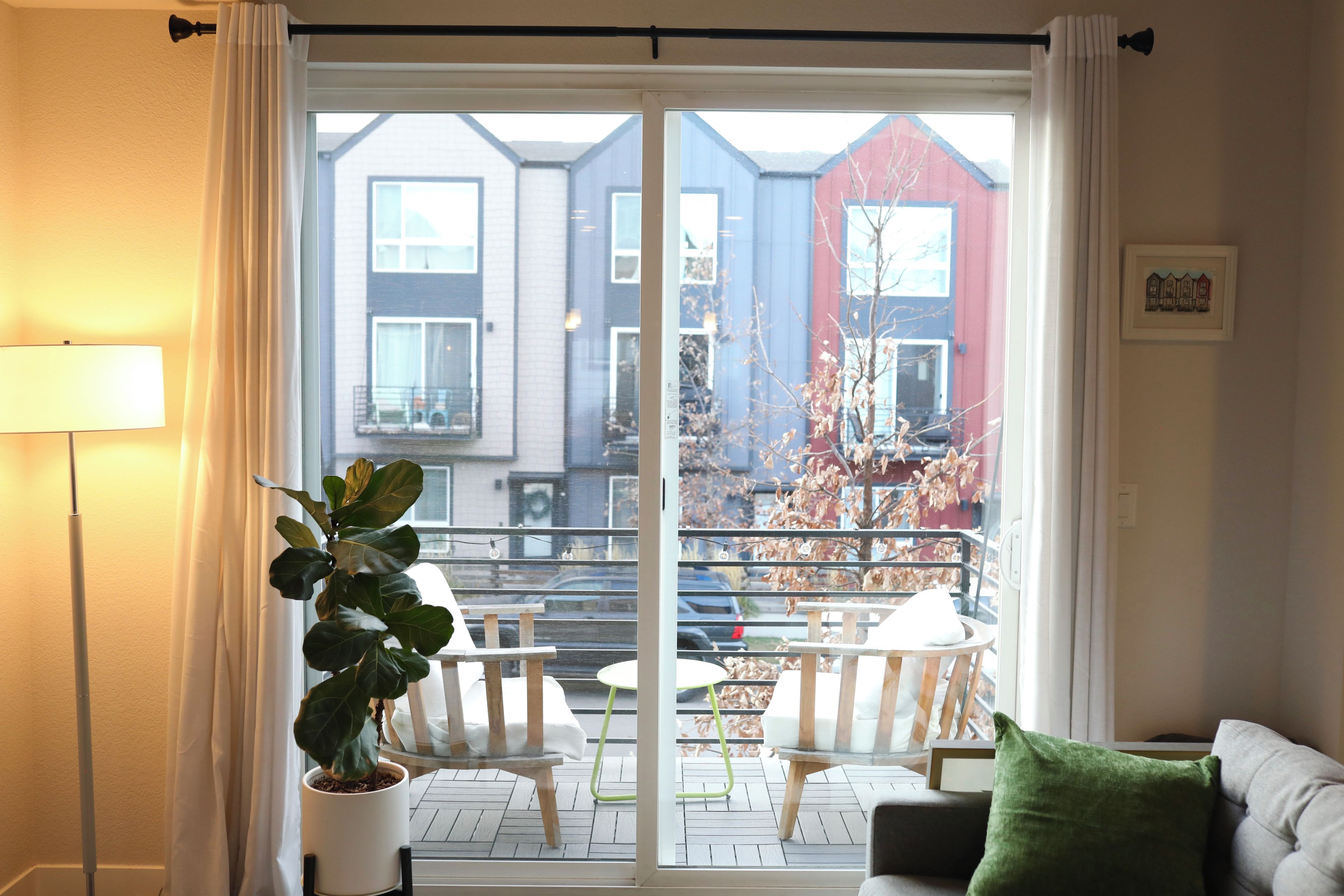 A living room with a large sliding glass door leading to an outdoor balcony with a view of a residential area.