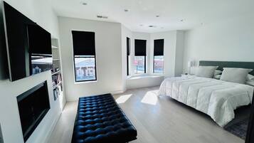 Un dormitorio moderno con cama, un banco y un televisor montado en la pared.