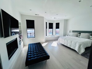 Une chambre à coucher moderne avec un lit, un banc et un téléviseur fixé au mur.