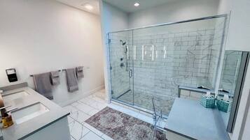 Un baño moderno con cabina de ducha de vidrio, un espejo grande y un tragaluz.