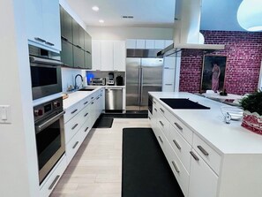Una cocina moderna con muebles blancos, electrodomésticos de acero inoxidable y una alfombra negra.