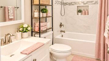 A bathroom with a white sink, a toilet, a shower with a glass door, and a vanity with a mirror and shelves.