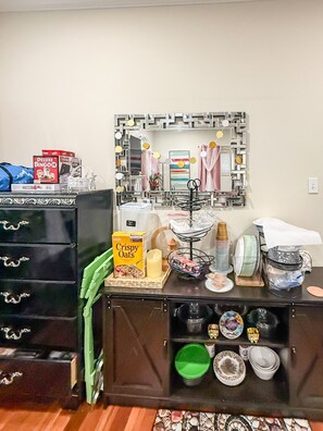 A kitchenette with a refrigerator, a microwave, a sink, and a countertop with various items including a cereal box, a candle, and a decorative mirror. - Mandale Ct - Welcoming Two-Story Shared Home in Fort Washington (Fort Washington)