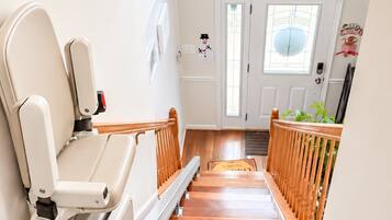 A wooden staircase with a handrail, a white door with a window, and a wall-mounted snowman decoration.