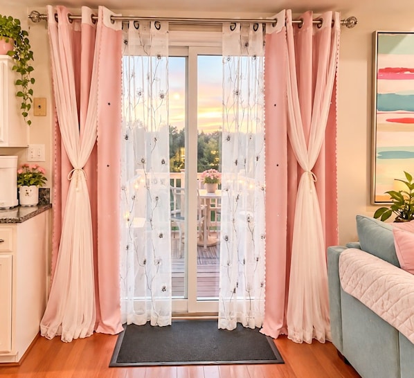 A room with a sliding glass door, a sofa, a coffee table, and a potted plant.