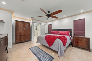 A bedroom with a bed, a ceiling fan, a wardrobe, and a nightstand. - The Pool House | Spa, Game Room & Home Gym (Cape Coral)