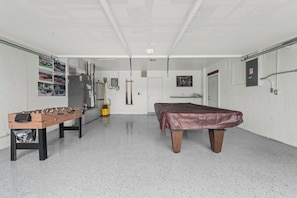 Een kamer met een tafelvoetbaltafel, een pooltafel en een stofzuiger.