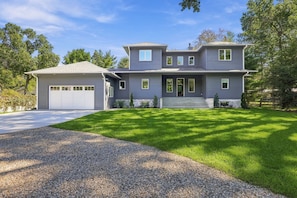 A two-story house with a garage, a front porch, and a well-maintained lawn. - Luxury pool house with association beach access! (New Buffalo)