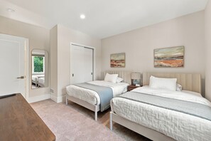 A bedroom with two beds, a wooden table, and a mirror. - Luxury pool house with association beach access! (New Buffalo)