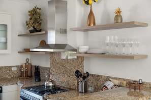 A modern kitchen with granite countertops, a gas stove, and stainless steel appliances. - The Golden Palm Villa (Noord)