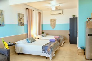 A hotel room with two beds, a desk, a chair, a wardrobe, and a ceiling fan. - Mountain Retreat with Boquerón Bay Views & Heated Saltwater Pool - 3B (Cabo Rojo)