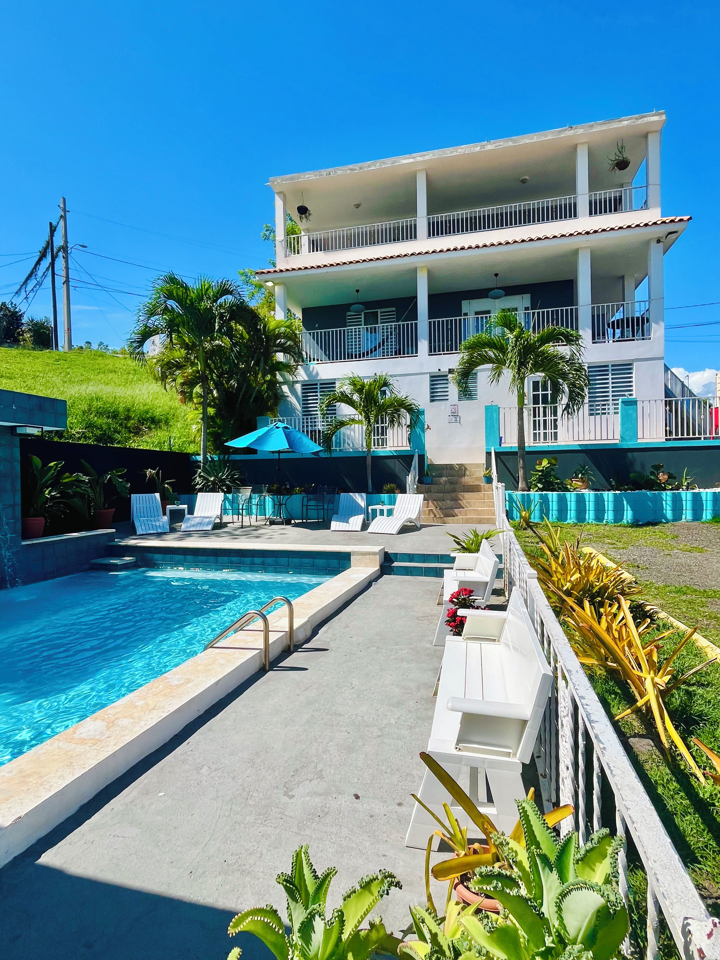 A swimming pool area with lounge chairs and a building with balconies.