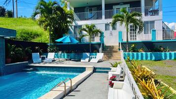 A swimming pool area with lounge chairs and a building with balconies.