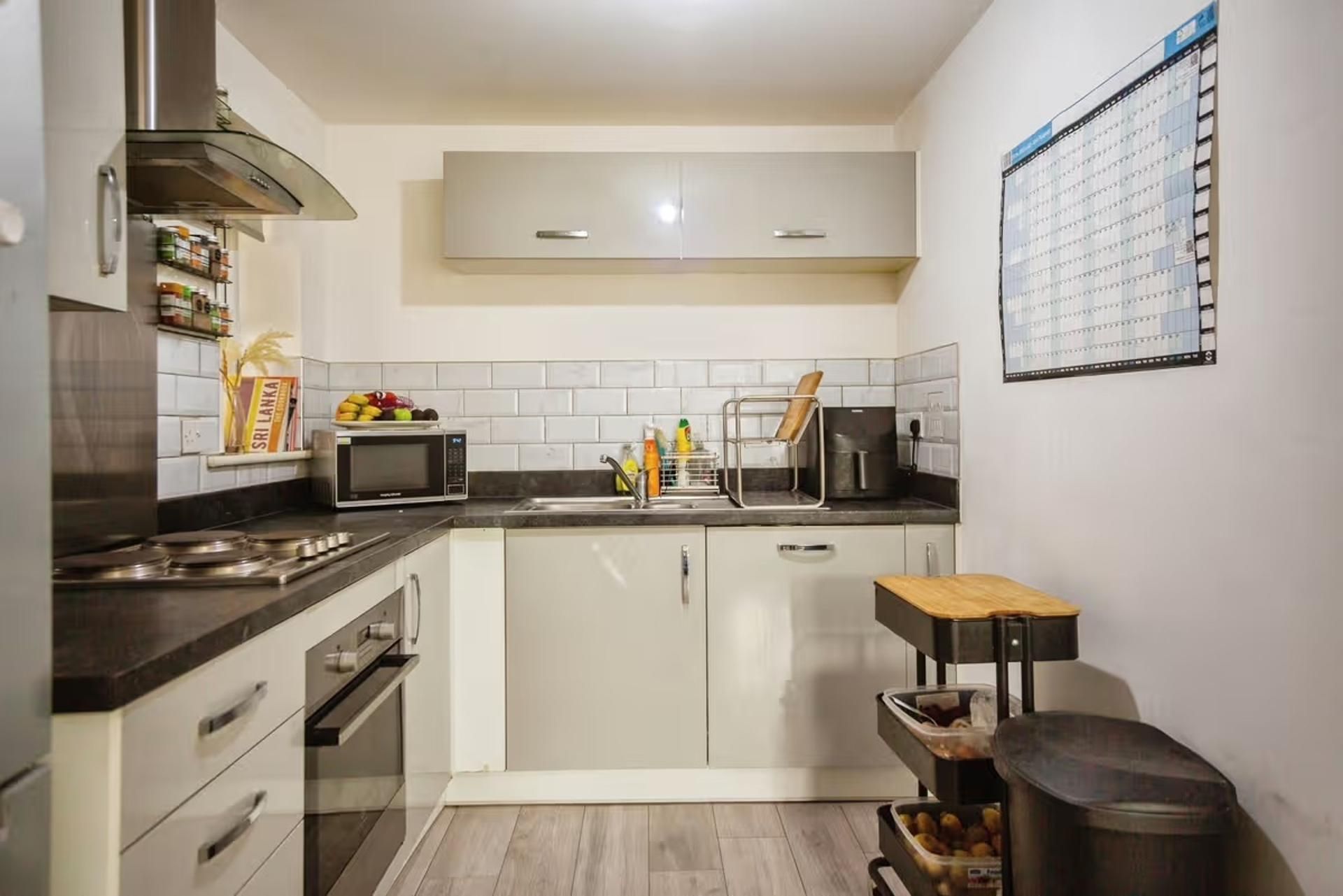 Una cocina pequeña con microondas, lavamanos y armarios.