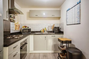 A compact kitchen with a microwave, sink, and cabinets. - Apartment Sleeps 4 With Balcony (Erith)