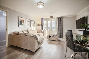 A living room with a sofa, a glass table, and a TV. - Apartment Sleeps 4 With Balcony (Erith)