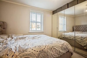 A bedroom with a bed, two windows, a wardrobe, and a mirror. - Apartment Sleeps 4 With Balcony (Erith)