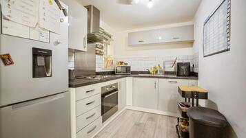 A kitchen with white cabinets, a stainless steel refrigerator, a microwave, and a water dispenser.
