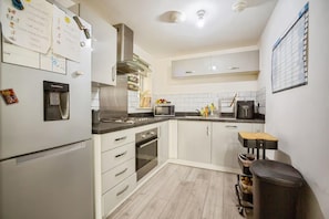 A kitchen with white cabinets, a stainless steel refrigerator, a microwave, and a water dispenser. - Apartment Sleeps 4 With Balcony (Erith)