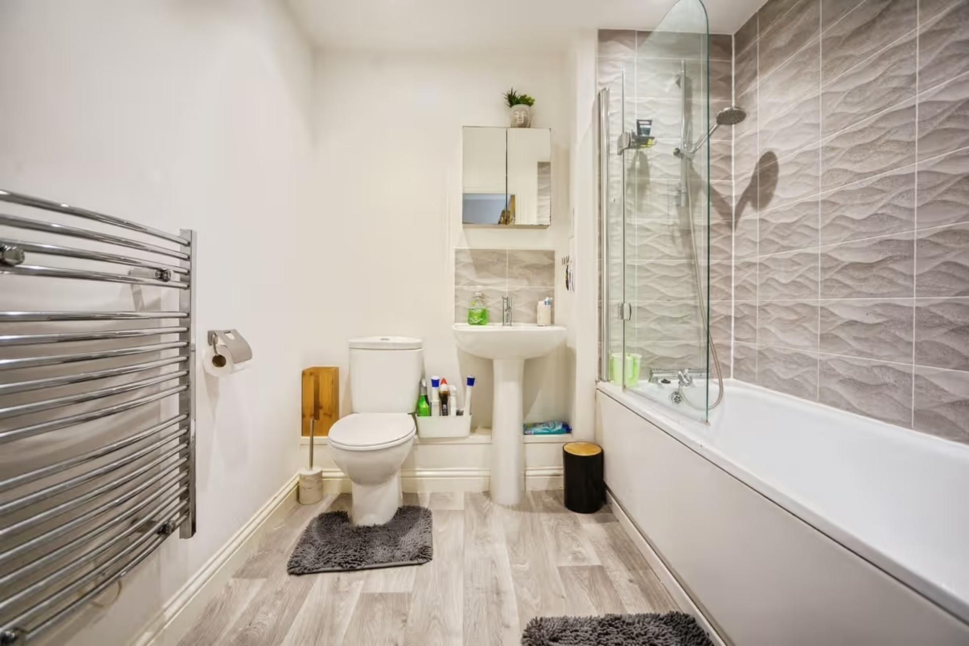 A modern bathroom with a glass-enclosed shower, a white toilet, and a sink.