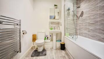 A modern bathroom with a glass-enclosed shower, a white toilet, and a sink.