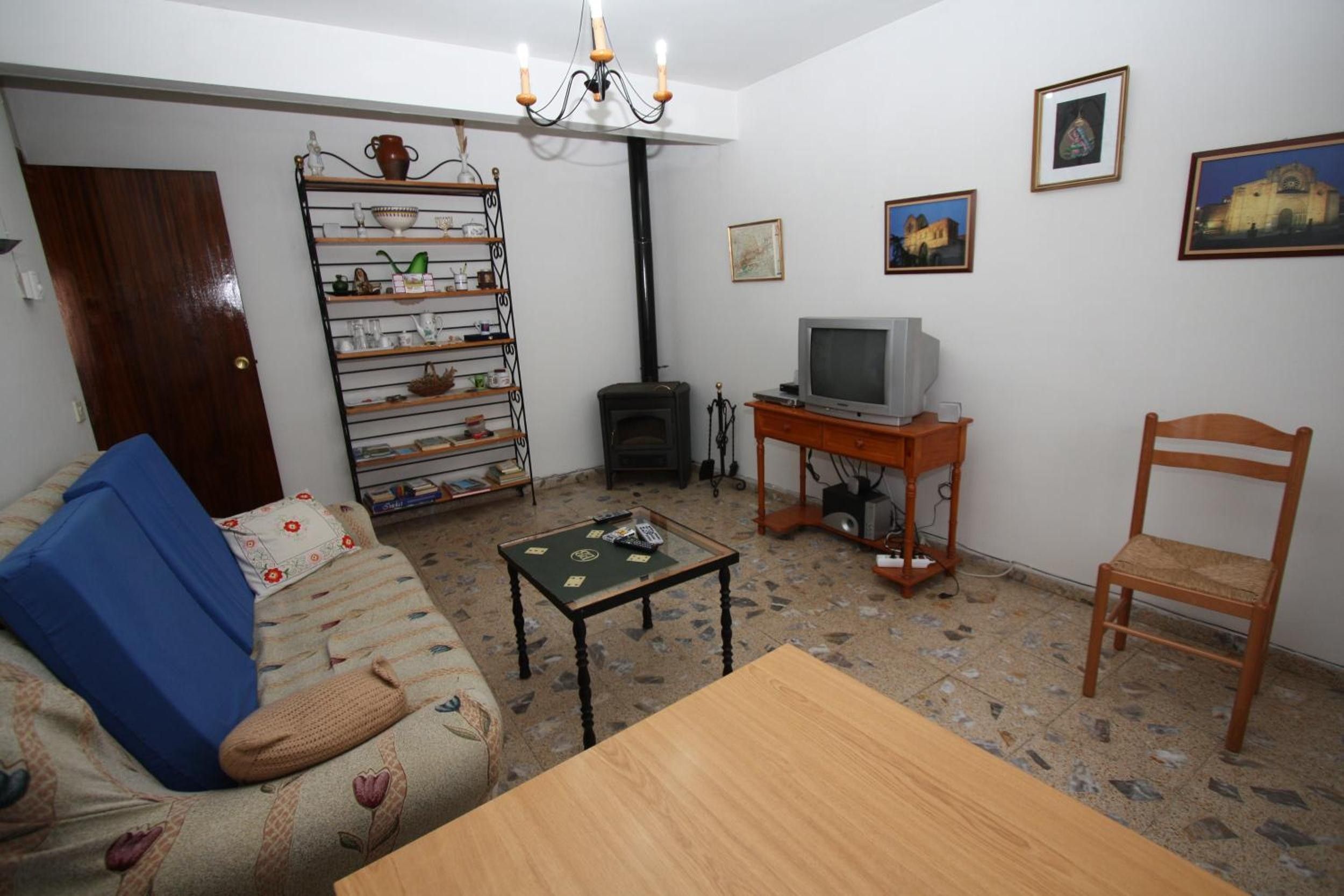 A living room with a sofa, a table, a television, a fireplace, and a bookshelf.