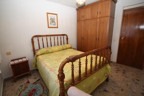 A bedroom with a wooden bed, a small bedside table, a wardrobe, and a door. - Country House 'Casa Rural El Nido' (Solana de Ávila)