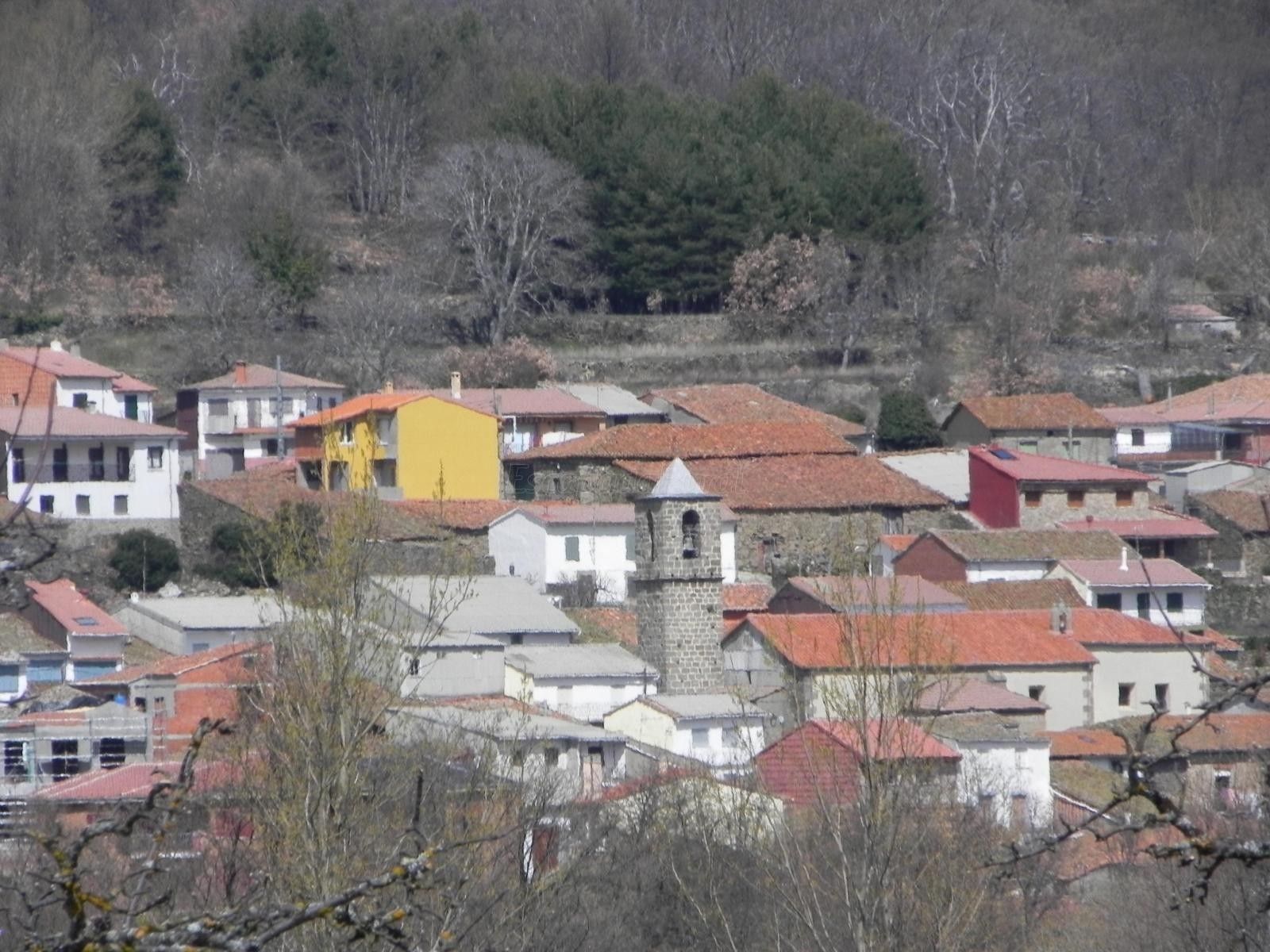 A cluster of buildings with red-tiled roofs, some with visible chimneys, and a prominent yellow building in the center.