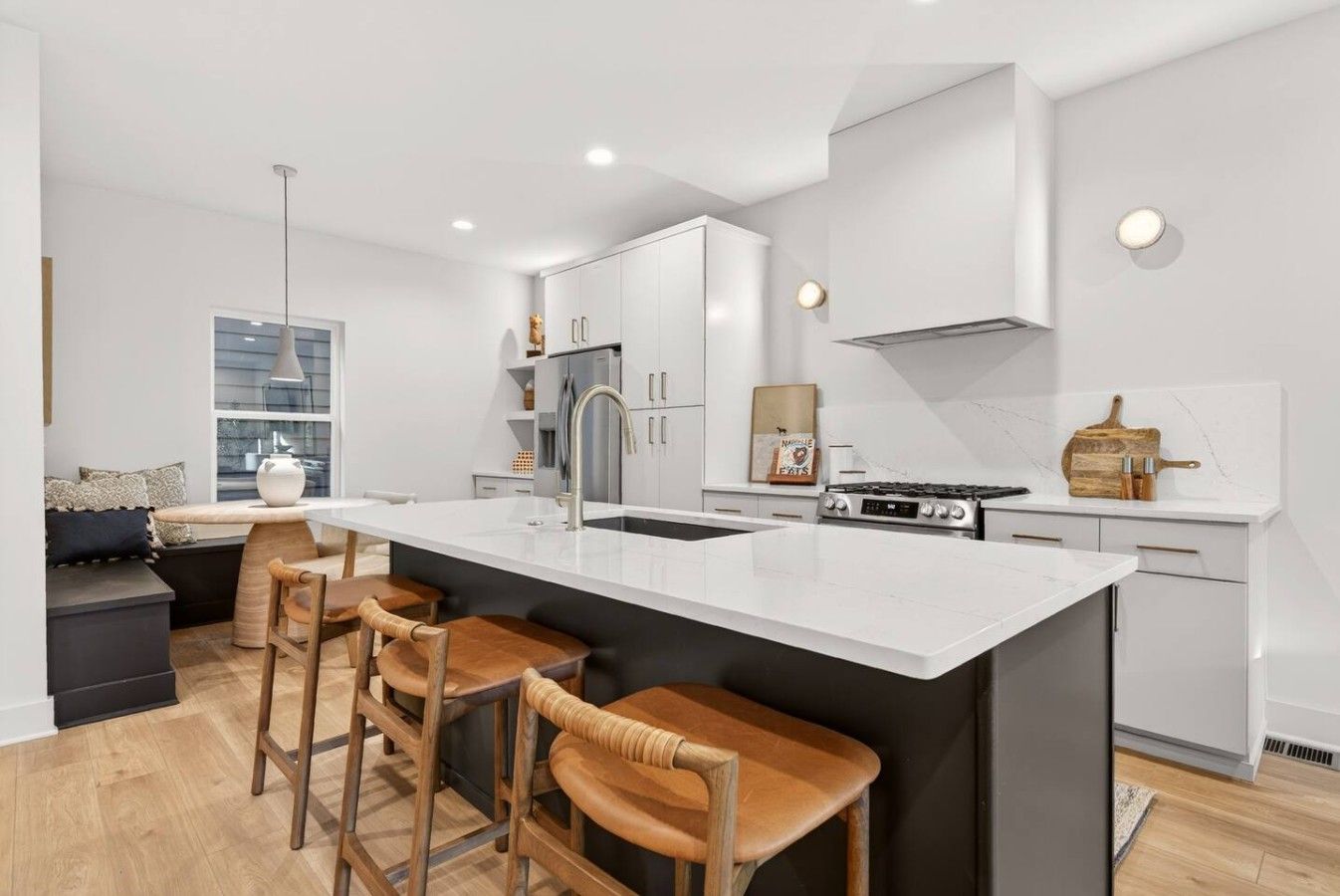 A modern kitchen with a central island, bar stools, and a stove.