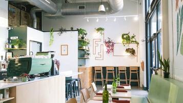 A modern kitchen with a green appliance, wooden bar stools, and a seating area with tables and chairs.