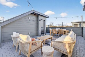 A covered outdoor patio with wicker furniture, a table, and string lights. - Rooftop Lounge, Walk to Restaurants, 3 miles to Downtown (Nashville)