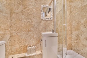 A bathroom with a glass shower enclosure, a white sink, and a marble-tiled wall. - En-Suite Double with Parking · Walk to Whitby Abbey & 199 Steps (North Yorkshire)