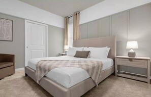 A bedroom with a large bed, a nightstand with a lamp, a chair, and a door. - 7BR house with private pool in Windsor Island (Davenport)