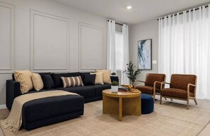 A modern living room with a dark sofa, a round coffee table, and a brown armchair. - 7BR house with private pool in Windsor Island (Davenport)