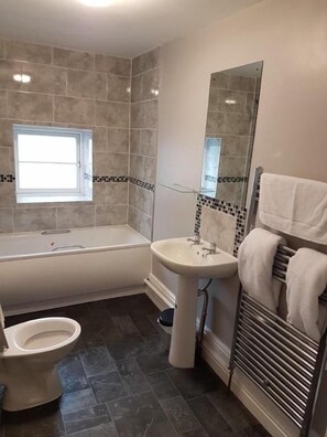 A bathroom with a bathtub, toilet, sink, and a towel rack. - The Five Bells (Ringwould)