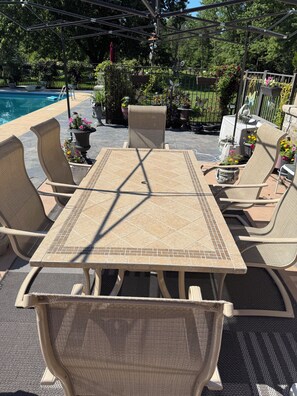Una veranda con tavolo e sedie, una piscina e piante in vaso.