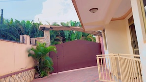 A gated entrance to a building with a tiled pathway leading to a balcony. - C&K Homes . (Kampala)