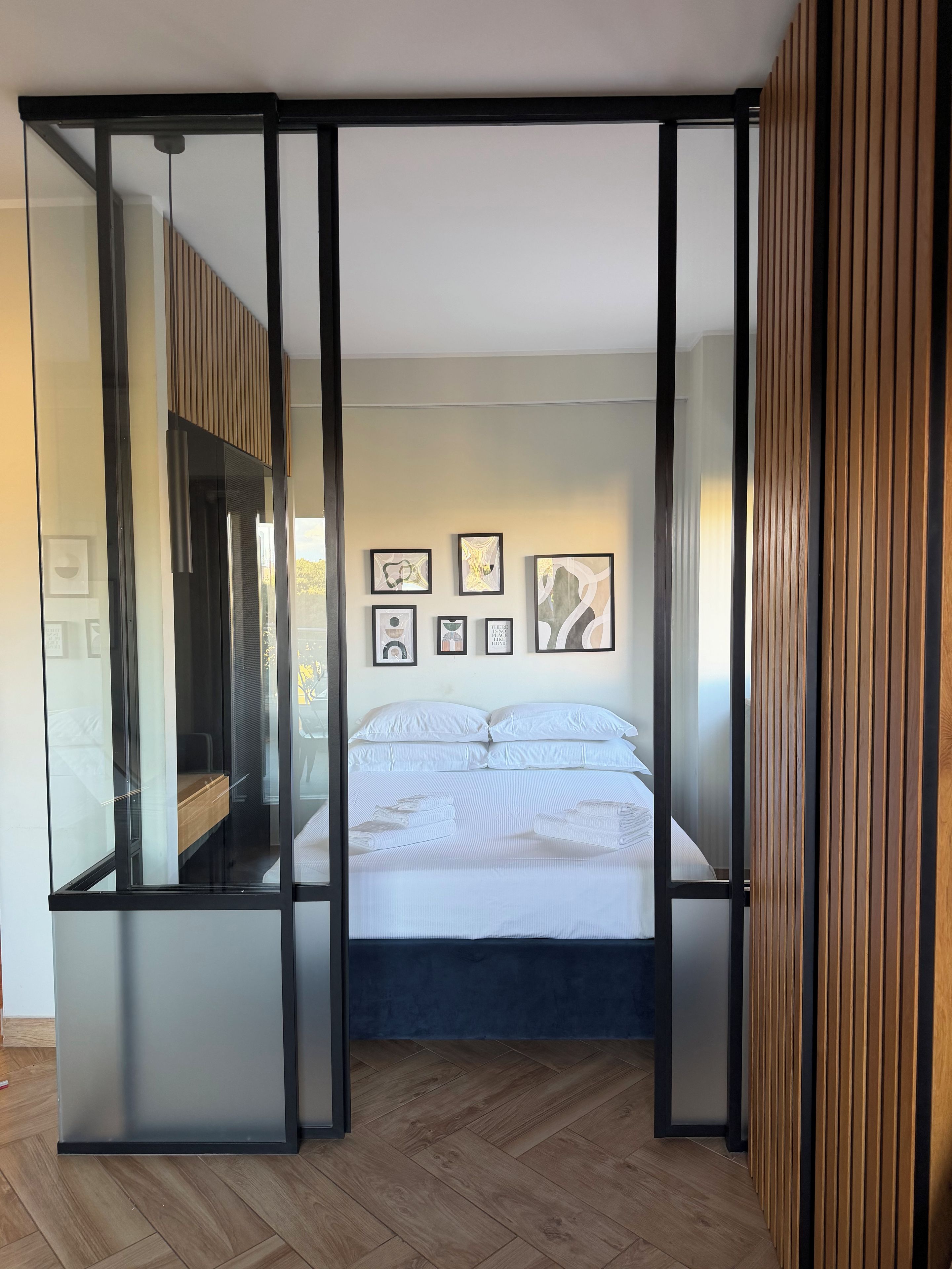 Ein Schlafzimmer mit einem Bett, einem Kleiderschrank und einer Wand mit gerahmten Bildern.